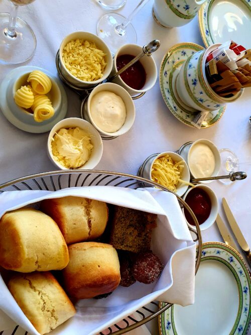 Freshly baked warm scones, served with cheese, clotted cream, Chantilly cream, and a bowl of strawberry jam.