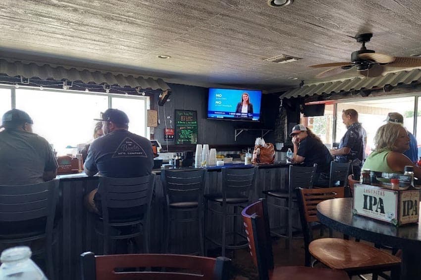 Golfers enjoying a cocktail and food at the 19th Hole Bar and Grill after a round on the Rivers Edge Golf Course. Windows reveal a view of the Colorado River. Photo by Kathy Condon