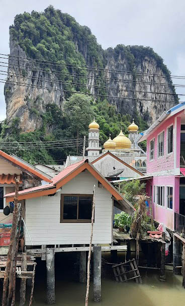 A beautiful mosque towering above the sea village with an imposing limestone rock served as a backdrop