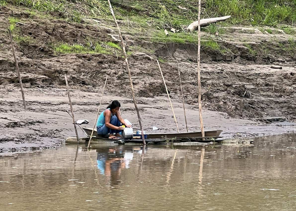 A woman washing cookware in the Amazon scaled