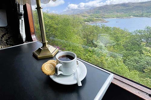 Tea is served in the first-class car aboard the Jacobite Express as you cruise through the Scottish Highlands.