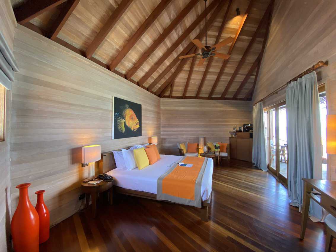 The bedroom of an elegant, over-water villa at Mirihi Island Resort.