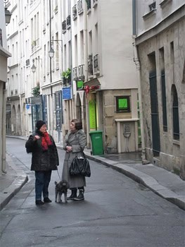 The neighbors chat on a street in Paris.