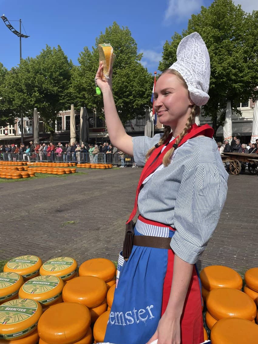 Market girl with massive wheels of cheese in Alkmaar. 
