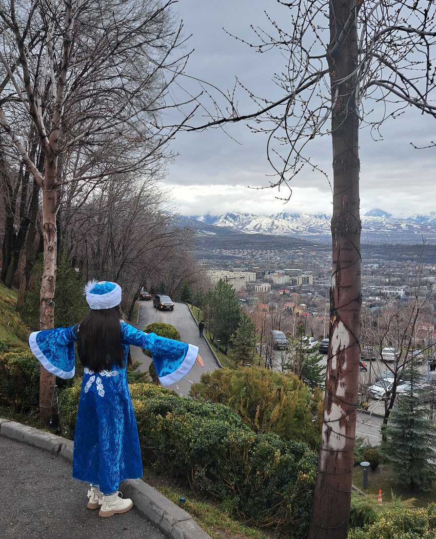 A little girl in Kazakh clothing enjoys the view at Kok Tobe