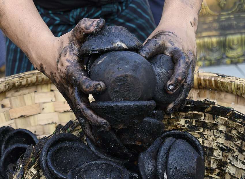 Buddhist devotees and monks present offerings and prayers in the form of oil lamps at the Shwedagon Pagoda in Yangon, Myanmar. Temple workers have the messy job of cleaning up the used vessels.