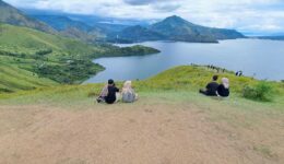 People relax on the grassy hill overlooking the lake at Holbung Hill