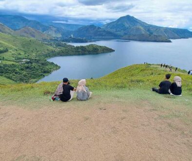 People relax on the grassy hill overlooking the lake at Holbung Hill