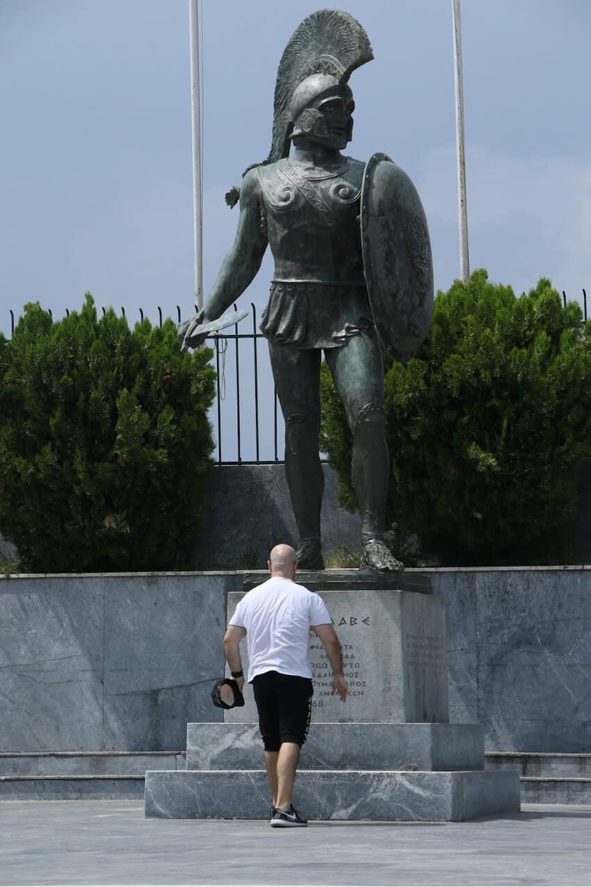 Greece's Peloponnese Region from Corinth to Areopoli 5 a man walking up stairs in front of a statue of a warrior