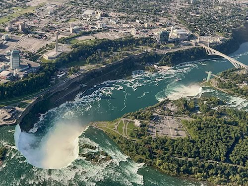 Niagara Falls from a helicopter including all three falls and pedestrian bridge.