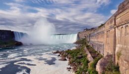 Horseshoe Falls in Niagara with spray in the air and River with stone wall.
