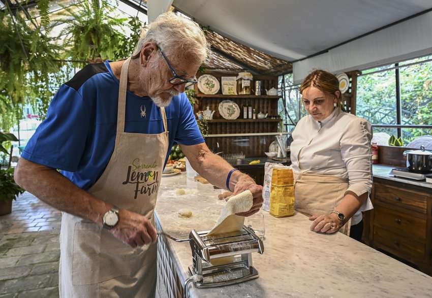 Ed carefully caresses ravioli dough through a pasta machine under the watchful eye of executive chef Francesca. in Sorrento Italy