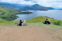 People relax on the grassy hill overlooking the lake at Holbung Hill
