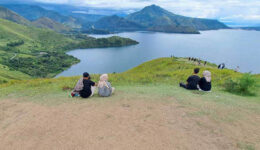 People relax on the grassy hill overlooking the lake at Holbung Hill