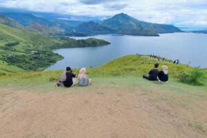 People relax on the grassy hill overlooking the lake at Holbung Hill
