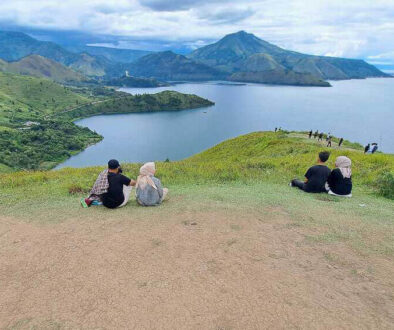 People relax on the grassy hill overlooking the lake at Holbung Hill